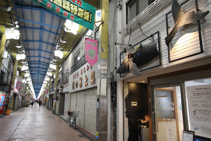 ジョイフル三の輪商店街のアーケードと、クジラの看板が目印の店舗